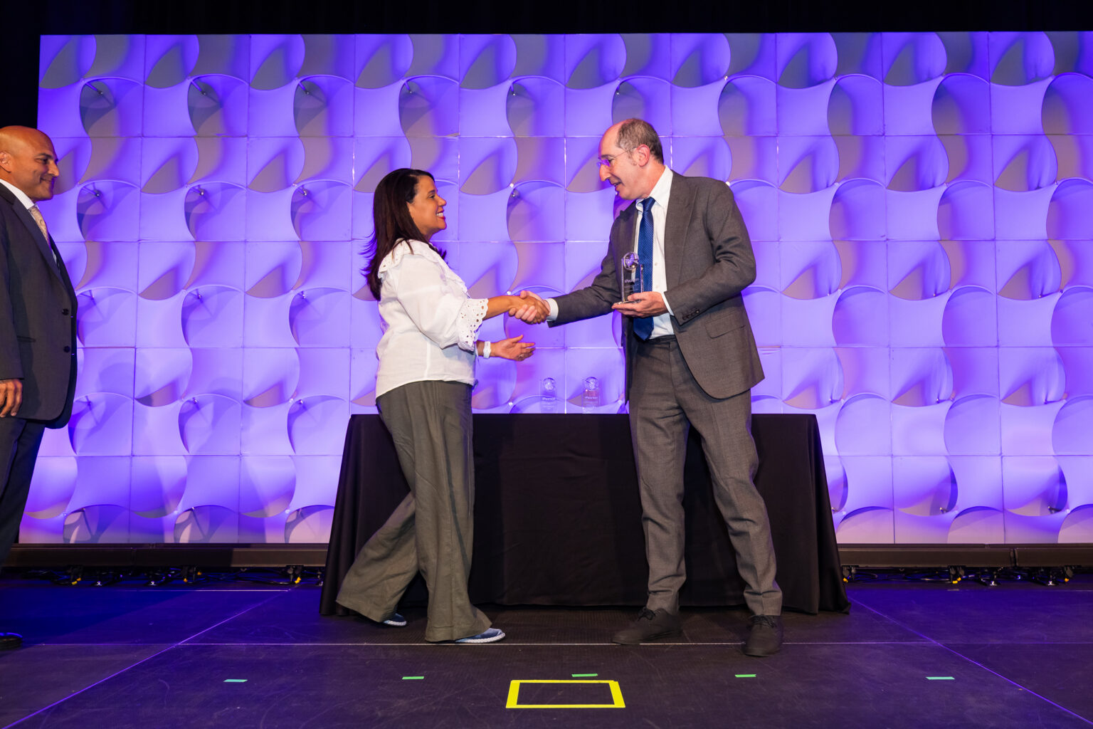 Entrega del reconocimiento a Josefina Thomas, Encargada de Proyectos Educativos de FL Betances & Asociados, en el escenario del Global Partner Summit 2026 (Anaheim, California).